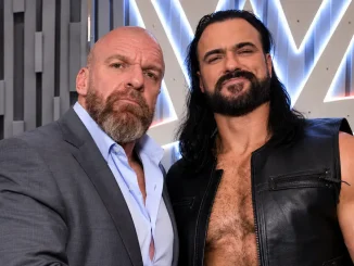 Triple H und Drew McIntyre posieren vor einem beleuchteten WWE-Logo, einer im grauen Anzug und der andere in einer schwarzen Lederweste.